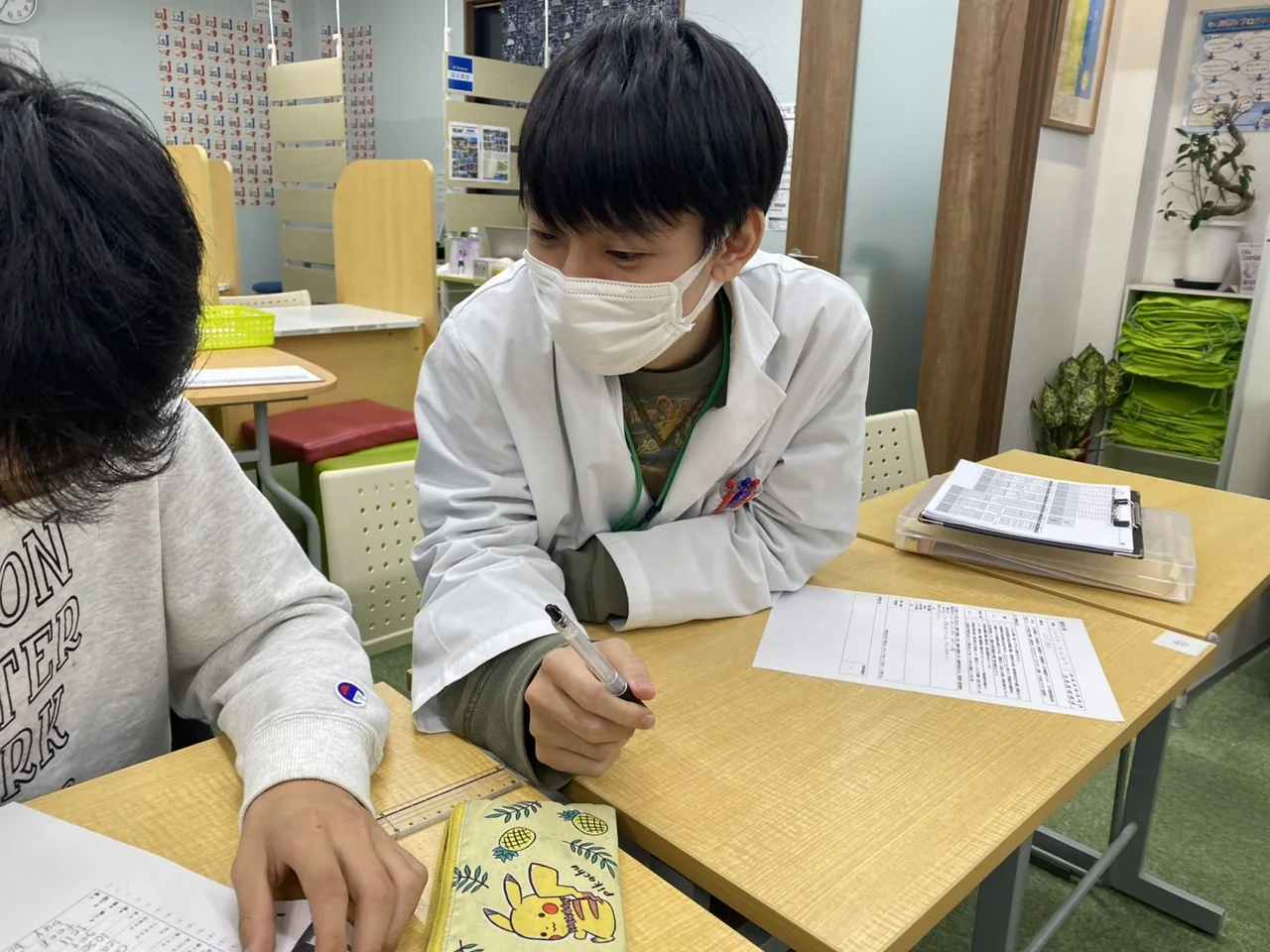 個個塾で先生が教材とノートを確認する様子