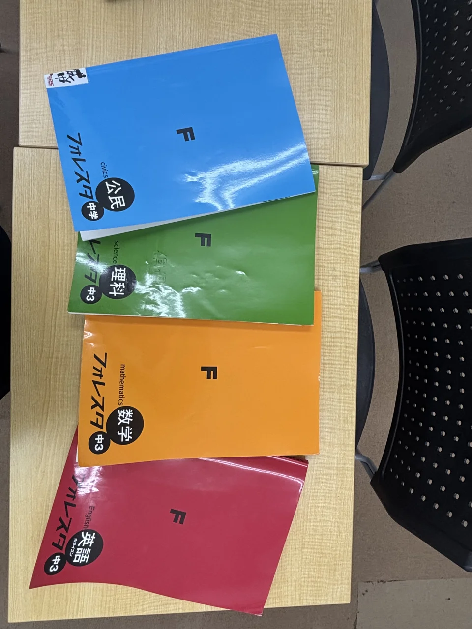 個個塾の机に並ぶ数学・英語・理科・社会の教材