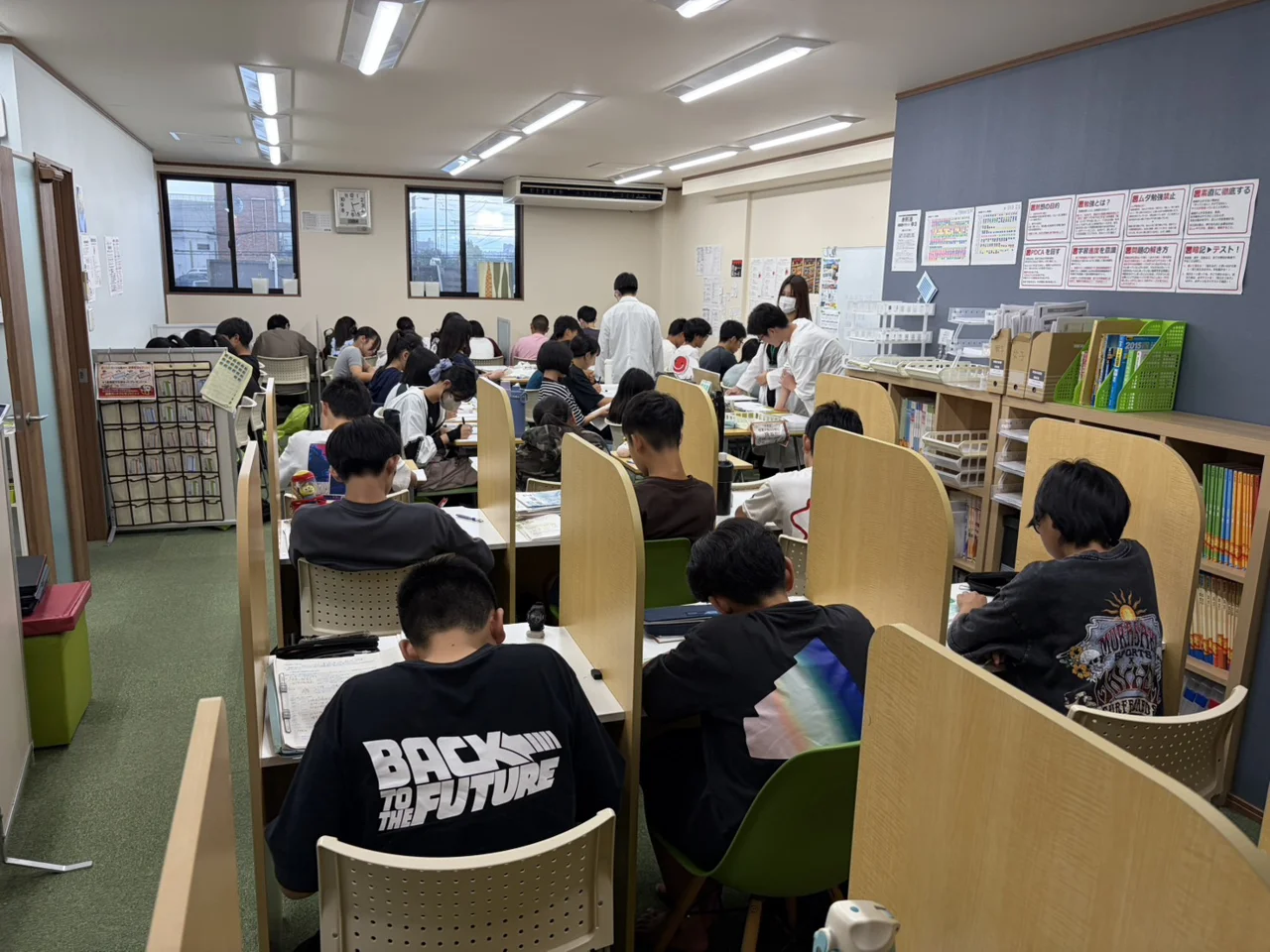 個個塾の教室で生徒たちが仕切りのある机に向かって学習する様子
